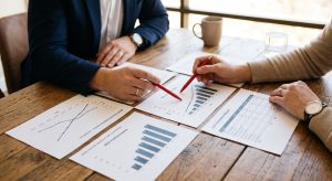 lose up of hands reviewing printed ROI graphs and lead generation reports, showing how a top SEO company Peachtree City measures success